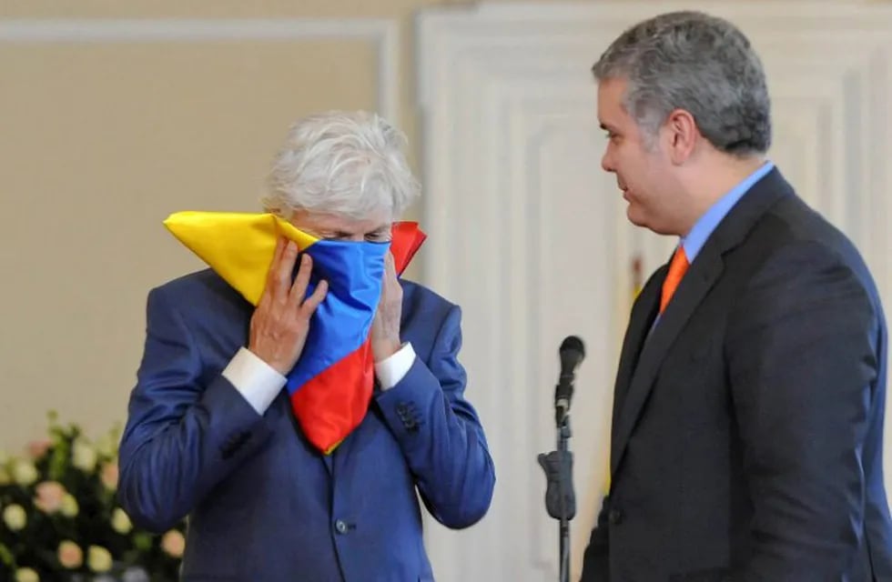 Handout picture released by the Colombian Presidency press office showing the former coach of the national football team, Argentine Jose Nestor Pekerman (L) kissing the Colombian national flag after it was given to him by Colombian President Ivan Duque in gratitude for his task at the helm of the Colombian squad, at the Casa Narino palace in Bogota, on September 17, 2018. (Photo by HO / Colombian Presidency / AFP) / RESTRICTED TO EDITORIAL USE - MANDATORY CREDIT \
