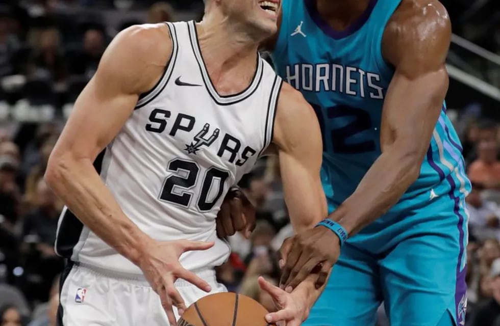 Charlotte Hornets center Dwight Howard (12) tries to strip the ball from San Antonio Spurs guard Manu Ginobili (20) during the second half of an NBA basketball game, Friday, Nov. 3, 2017, in San Antonio. San Antonio won 108-101. (AP Photo/Eric Gay)