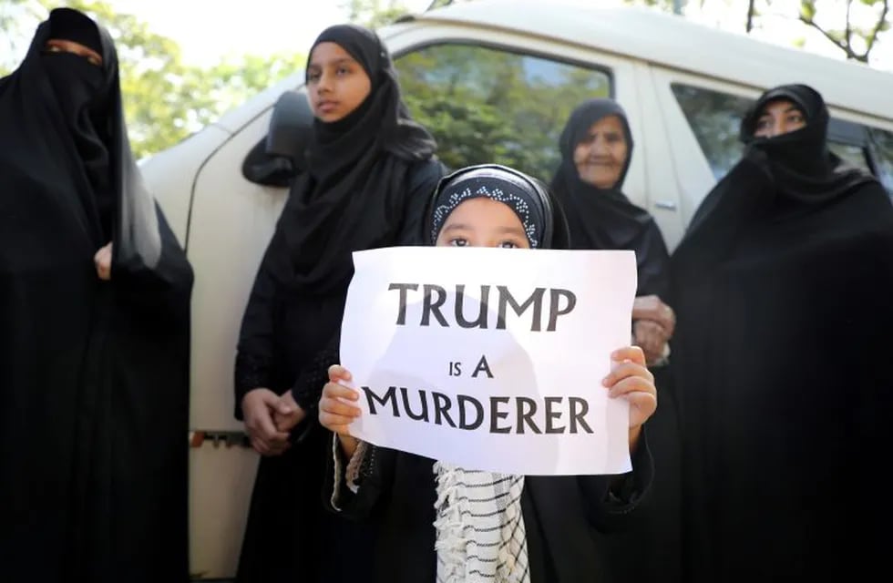 FILE PHOTO: A girl holds a sign reading “Trump is a murderer” during a condolence ceremony for Iranian Major-General Qassem Soleimani, who was killed in a airstrike near Baghdad, outside the Embassy of Iran in Kuala Lumpur, Malaysia, January 7, 2020. REUTERS/Lim Huey Teng/File Photo