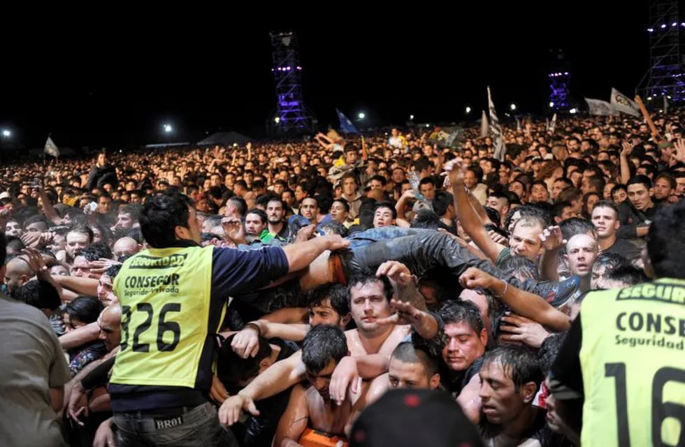 Security personnel remove a fan who was dancing in the mosh pit during Argentine singer Indio Solari's show in Olavarria, Argentina, Saturday, March 11, 2017. Officials say two people died in a crush during Solari's massive rock concert. (AP Photo/Hernan 