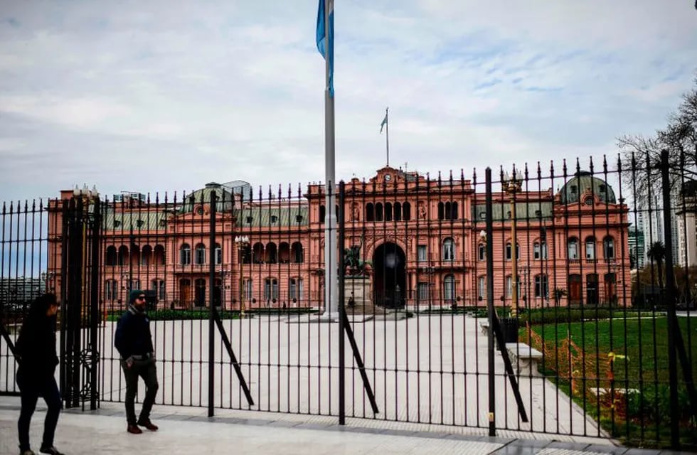 People walk in front the Casa Rosada presidential house in Buenos Aires, on August 30, 2019. - Recession-hit Argentina has been whipped by market volatility since business-friendly Argentine President Mauricio Macri was trounced in party primaries three weeks ago by leftist challenger Alberto Fernandez. (Photo by RONALDO SCHEMIDT / AFP)