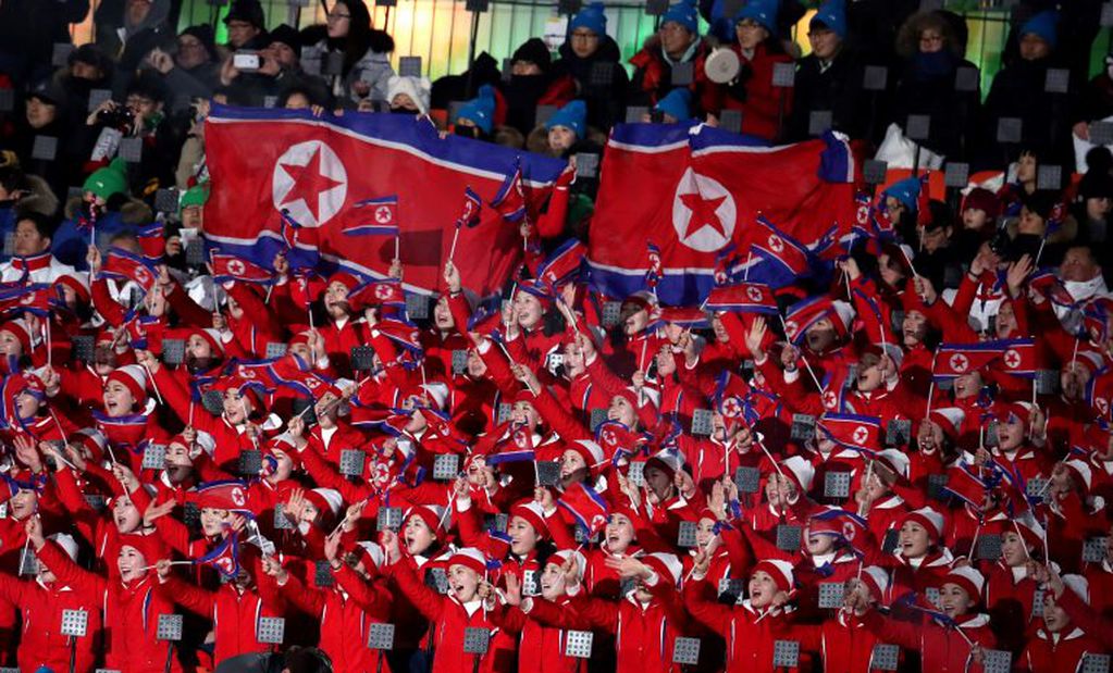 Animadoras norcoreanas ondean banderas de su país.