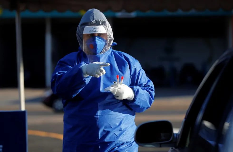 A nurse, dressed in a hazmat suit as a protection against the new coronavirus, points at a driver to tell him he is next to be tested for a COVID-19 disease, at a checkpoint in San Lorenzo, on the outskirts of Asuncion, Paraguay, Tuesday, April 28, 2020. (AP Photo/Jorge Saenz)