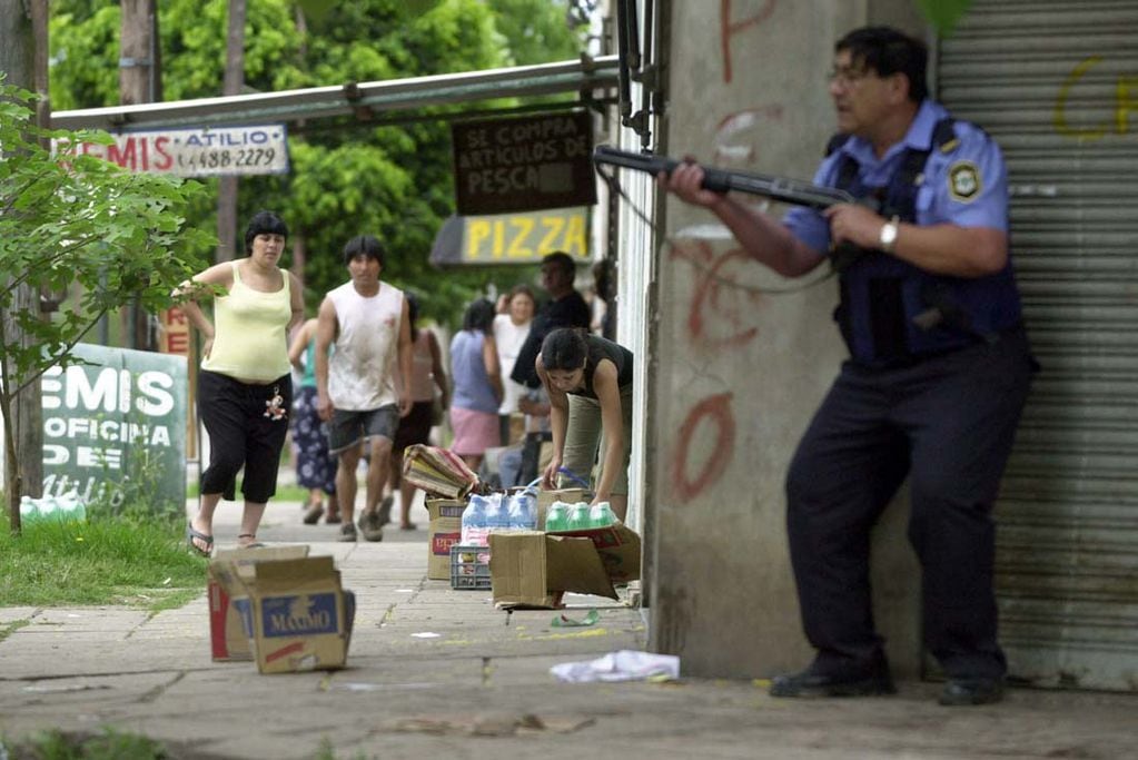 Saqueos en Ciudadela y un policía de Buenos Aires con su arma.