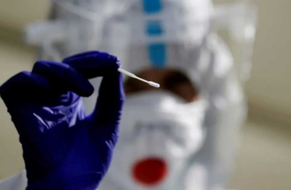 A medical staff member wearing a protective suit holds a swab as he waits for people who will be tested for the coronavirus disease (COVID-19) at a newly opened drive-in sampling station in Prague, Czech Republic, October 7, 2020. REUTERS/David W Cerny