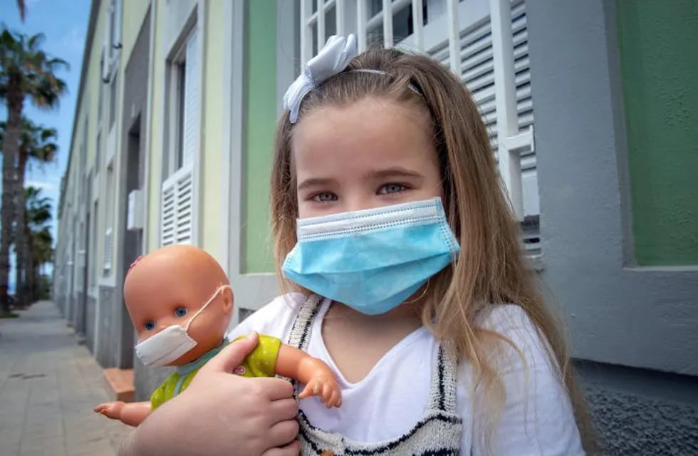 Naidelin, 5, and her doll pose wearing a face mask in the street in Santa Cruz on the Canary Island of Tenerife, on April 26, 2020 during a national lockdown to prevent the spread of the COVID-19 disease. - After six weeks stuck at home, Spain's children were being allowed out today to run, play or go for a walk as the government eased one of the world's toughest coronavirus lockdowns. Spain is one of the hardest hit countries, with a death toll running a more than 23,000 to put it behind only the United States and Italy despite stringent restrictions imposed from March 14, including keeping all children indoors. Today, with their scooters, tricycles or in prams, the children accompanied by their parents came out onto largely deserted streets. (Photo by DESIREE MARTIN / AFP)