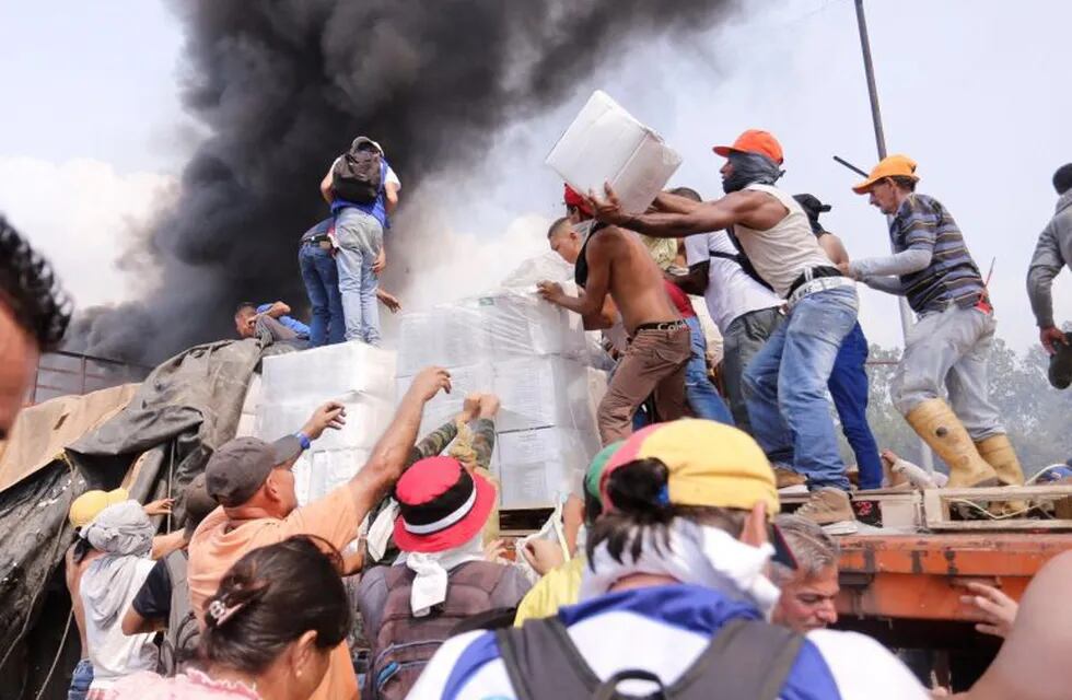 -FOTODELDIA- AME8150. UREÑA (VENEZUELA), 23/02/2019.- Personas intentan sacar parte de la ayuda humanitaria que se encuentra un camión que fue quemado, este sábado, en Ureña (Venezuela). Dos camiones con ayuda humanitaria solicitada por la oposición fueron quemados por la Policía Nacional Bolivariana en el lado venezolano del puente Francisco de Paula Santander, que conecta al país con Colombia, denunció la diputada Gaby Arellano. EFE/ Deibison Torrado