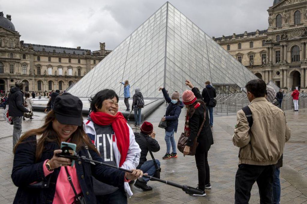 A visitor in a face mask poses for photographs outside the Louvre Museum which is closed due to staff worries over the coronavirus outbreak in Paris, France, on Monday, March 2, 2020. Group of Seven finance ministers will hold a teleconference this week to coordinate their response to the coronavirus outbreak, France’s Finance Minister Bruno Le Maire said Monday. Photographer: Adrienne Surprenant/BloombergA