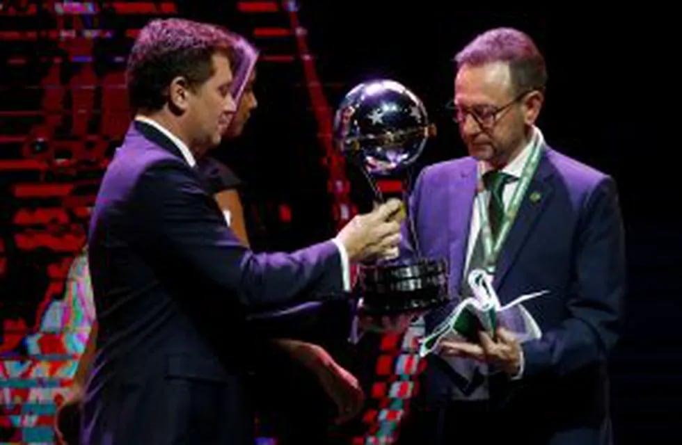 Conmebol President Alejandro Dominguez, left, presents the Sudamericana Championship trophy to Brazil's Chapecoense President Plinio de Nes during a Copa Libertadores soccer championship drawing ceremony, in Luque, Paraguay, Wednesday, Dec. 21, 2016. The first round of 58th edition of this championship will start on Jan. 23, 2017. (AP Photo/Jorge Saenz)
