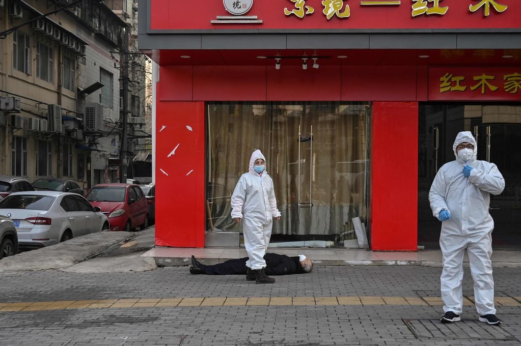 30 de enero de 2020 muestra a funcionarios con trajes protectores revisando a un anciano con una máscara facial que colapsó y murió en una calle cerca de un hospital en Wuhan. Hector Retamal / AFP