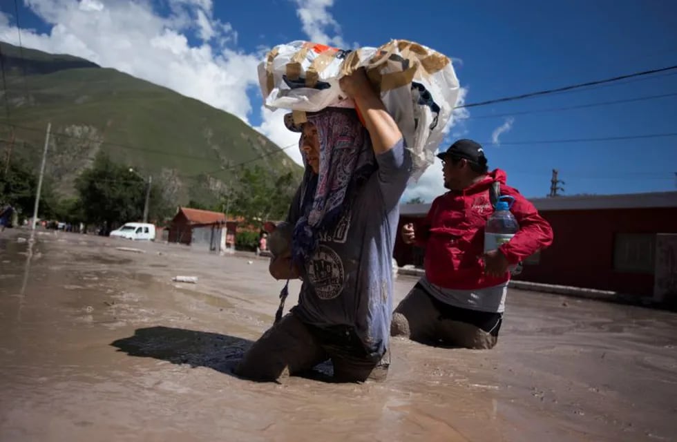 In this  Jan. 13, 2017 photo, residents wade waist deep in the mud, with rescued religious figures, in the town of Volcan, Jujuy province, Argentina. The statues will be taken to a secure place until cleanup efforts are completed. (Gianni Bulacio/Infoto via AP) jujuy volcan  jujuy desastre por alud de barro en volcan desastres naturales aludes