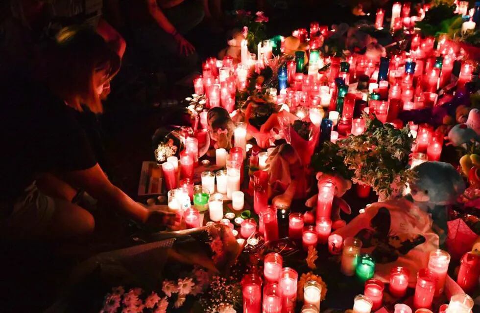People lay flowers, candles and other items at a makeshift memorial set up on the Las Ramblas boulevard in Barcelona as they pay tribute to the victims of the Barcelona attack, a day after a van ploughed into the crowd, killing 14 persons and injuring over 100 on August 18, 2017. \nDrivers have ploughed on August 17, 2017 into pedestrians in two quick-succession, separate attacks in Barcelona and another popular Spanish seaside city, leaving 14 people dead and injuring more than 100 others. Some eight hours later in Cambrils, a city 120 kilometres south of Barcelona, an Audi A3 car rammed into pedestrians, injuring six civilians -- one of them critical -- and a police officer, authorities said. / AFP PHOTO / Pascal GUYOT