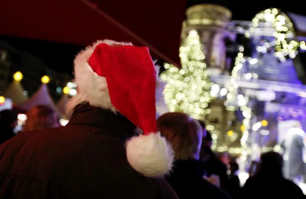 A man wears a Santa Claus hat as he walks in the illuminated Christmas market at Gendarmenmarkt square in Berlin, November 25, 2013.    REUTERS/Fabrizio Bensch      REUTERS/Fabrizio Bensch (GERMANY - Tags: CITYSCAPE SOCIETY RELIGION) alemania berlin  alemania decoracion navideña en berlin fiestas de fin de año