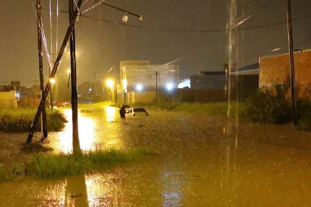 Auto inundado y flotando por el medio de la calle en el Barrio Universitario.